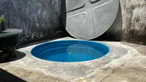 Estrutura da caixa d'água adaptada no solo da casa, como uma espécie de piscina. Há degraus que levam ao acesso do deque improvisado - Reprodução