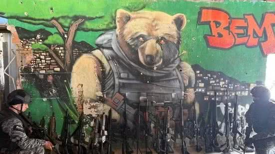 PM apresenta fuzis apreendidos em operação contra o CV; ao fundo, grafite em referência a Doca - Divulgação / PMERJ