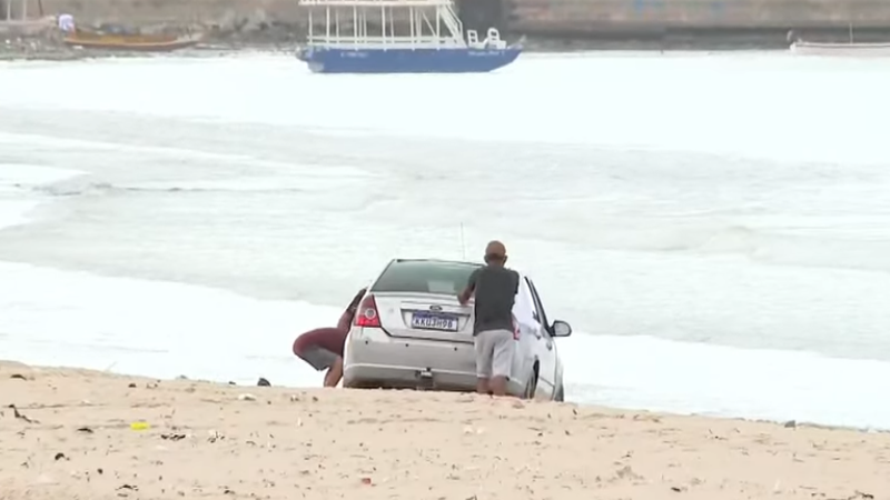 Carro atola após motorista invadir faixa de areia na Praia da Avenida, em Maceió