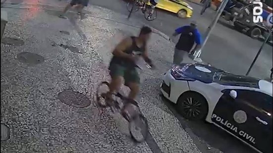 Davi Santos Machado, 21, suspeito de participação no linchamento que matou Cláudio Rafael Landeiro, chega à 12ª DP (Copacabana), no Rio de Janeiro, pedalando a bicicleta usada pela vítima na noite do crime - Divulgação / Polícia Civil RJ