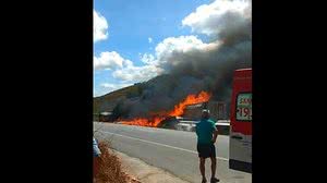 Motorista é socorrido pelo Samu, enquanto Corpo de Bombeiros tenta conter o fogo na carreta | Reprodução /