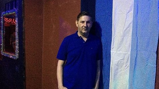 Karlos posa ao lado da bandeira G0Y, à entrada do bar; a inauguração está marcada para o dia 24 | UOL