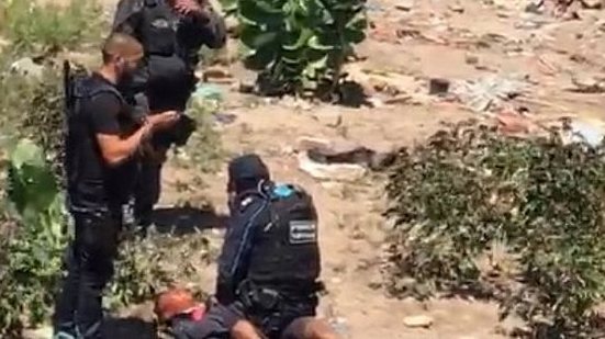 No vídeo, um suposto policial segura a vítima, enquanto o outro faz a prática do afogamento simulado (tortura na qual a água despejada sobre o pano na face inunda os pulmões e a vítima sufoca lentamente). | Reprodução/Vídeo