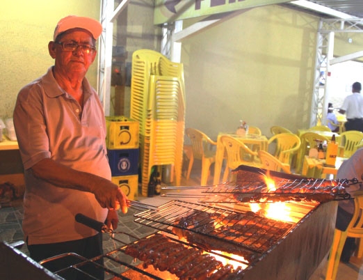 Seu Ferreira fica lá no fim do bar com sua singela churrasqueira preparando as melhores carnes 