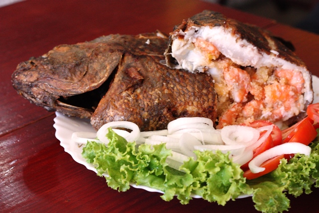 Tilápia sem espinha é cortada ao meio para mostrar a fartura da farofa com camarões