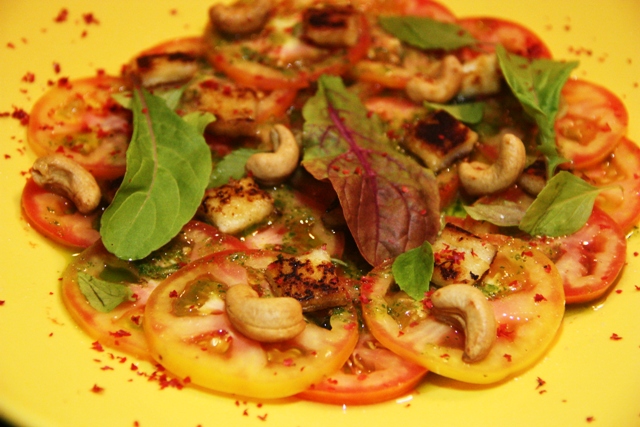Tomate virou carpaccio com castanha de caju, queijo coalho, manjericão, redução de vinagre balsâmico e azeite com torradas