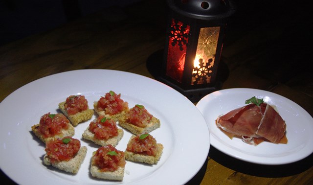 Pão com tomate, azeite, sal grosso e fatias de jamon (presunto de porco) e o charme da lamparina
