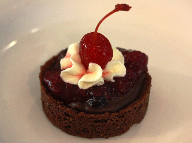 massa e ganache de chocolate meio amargo, coberto com calda de frutas vermelhas.