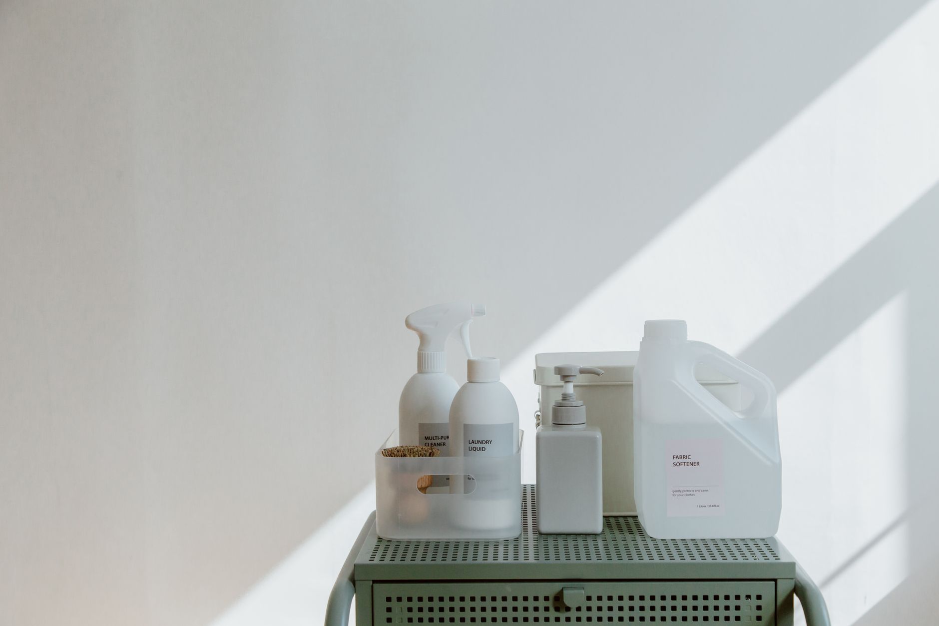 Arranjo estético de produtos de limpeza em recipientes minimalistas com suaves sombras.