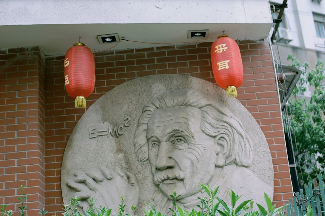 a statue of an old man with a red lantern in front of a brick building