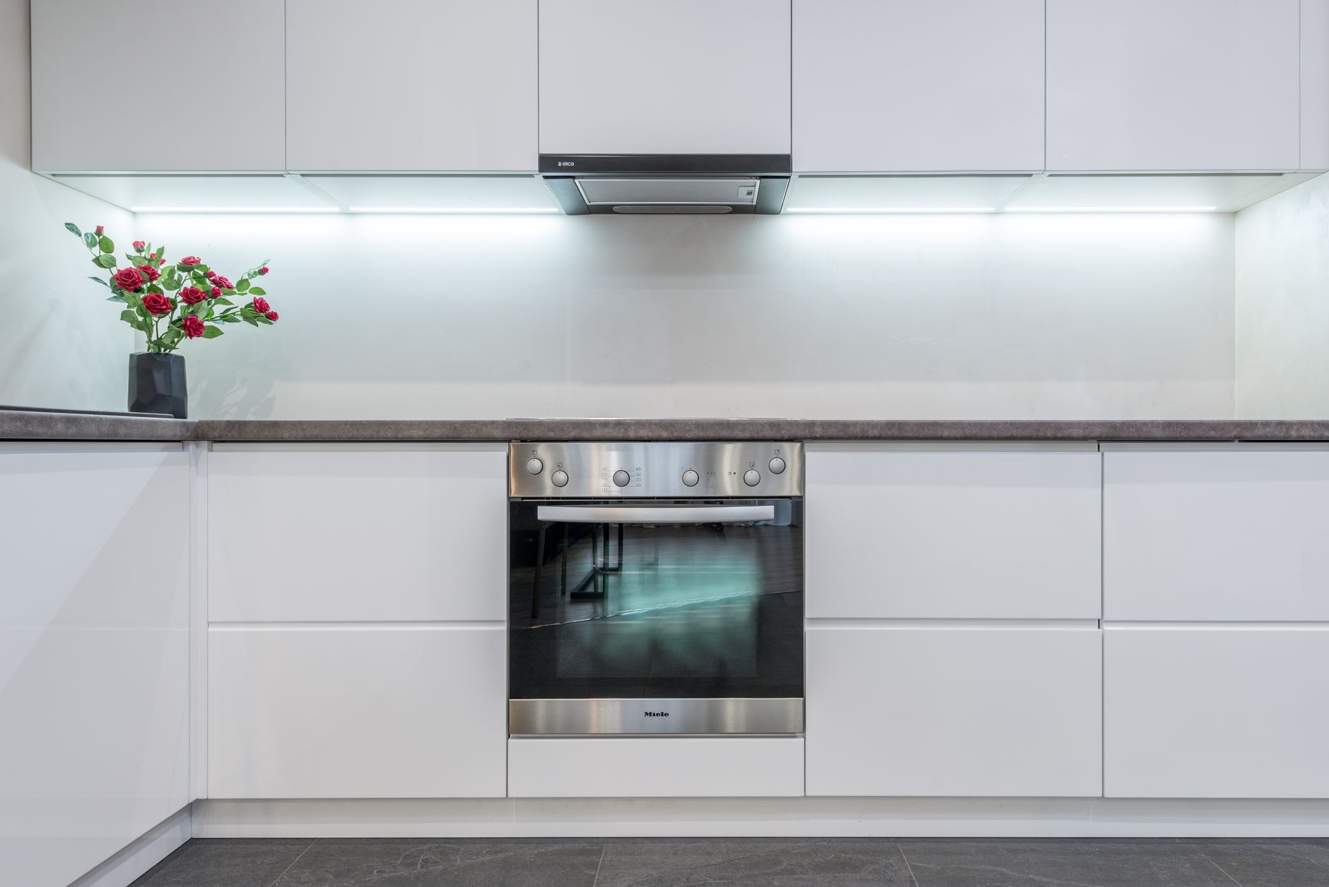 Cozinha elegante em branco com design contemporâneo e decoração floral.