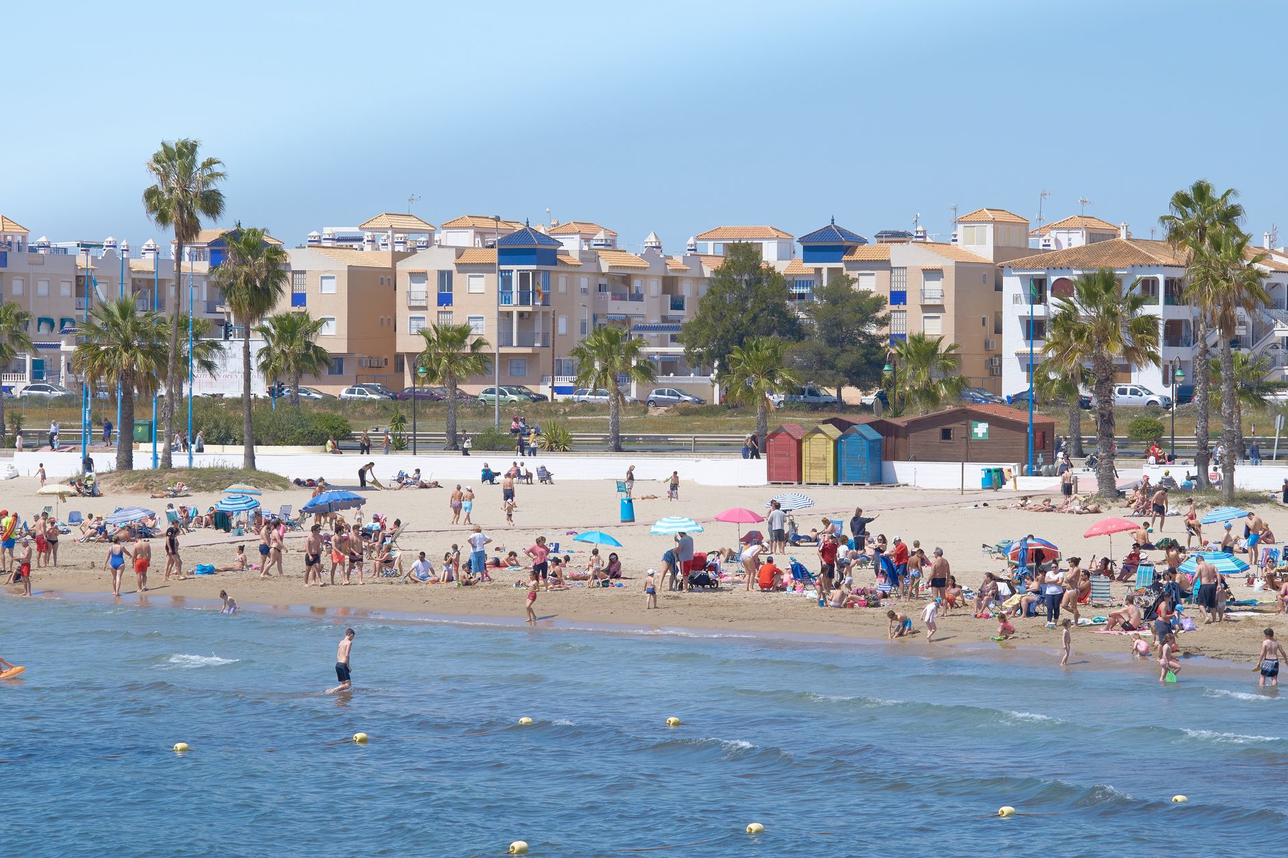 Aproveite um animado dia de verão em uma movimentada praia mediterrânea com pessoas curtindo o sol.
