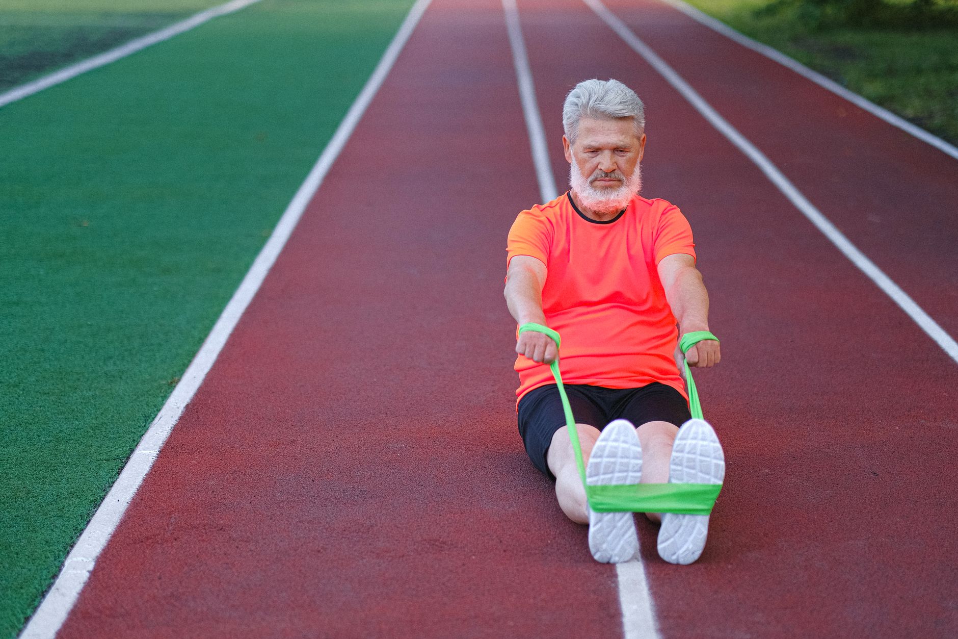 Idoso usando faixa de resistência em uma pista ao ar livre, promovendo fitness e vitalidade.