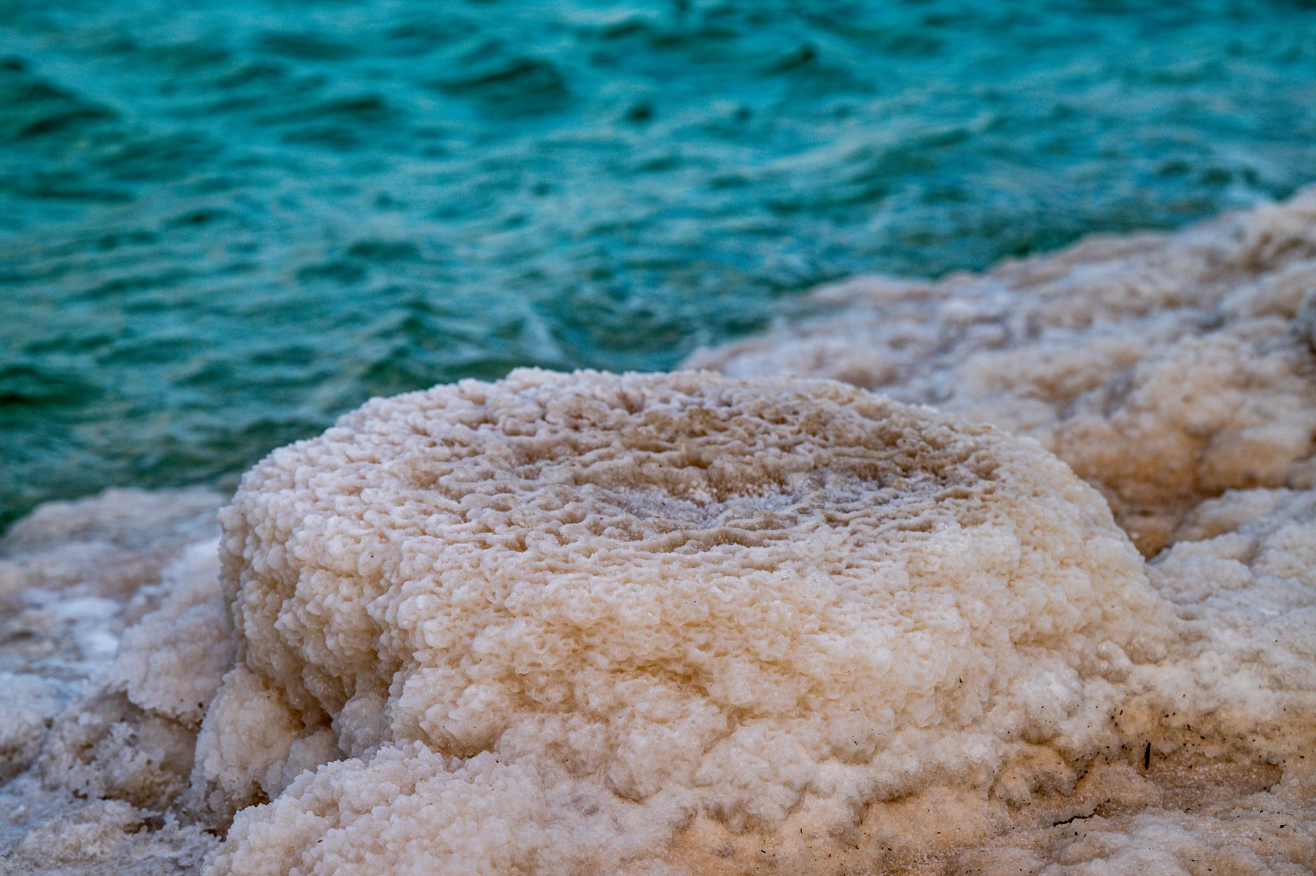 Vista de perto de formações de sal ao longo de uma costa azul vibrante, exibindo texturas naturais.