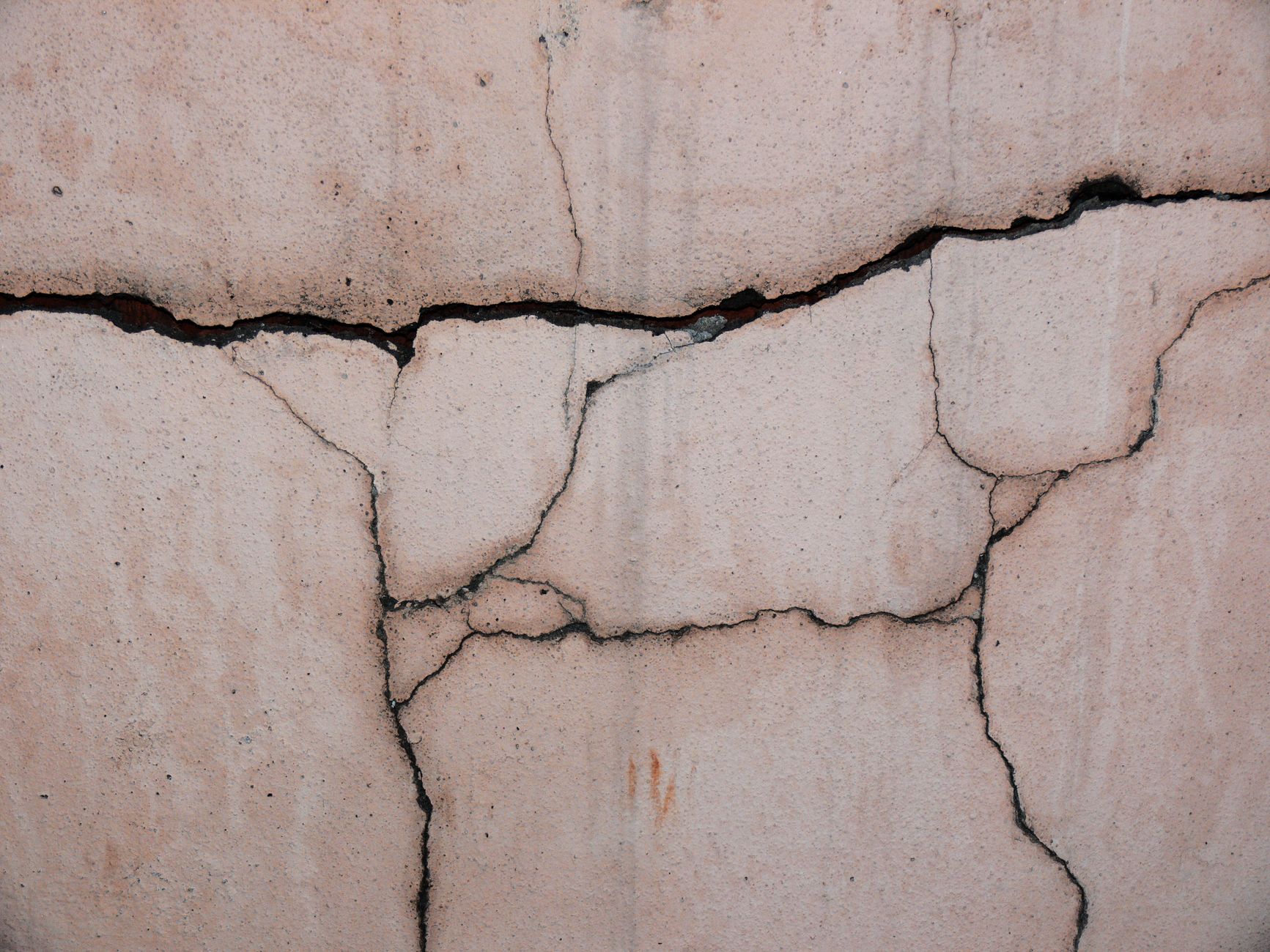 Close-up de uma parede de concreto rachada, destacando sua textura e padrões únicos.