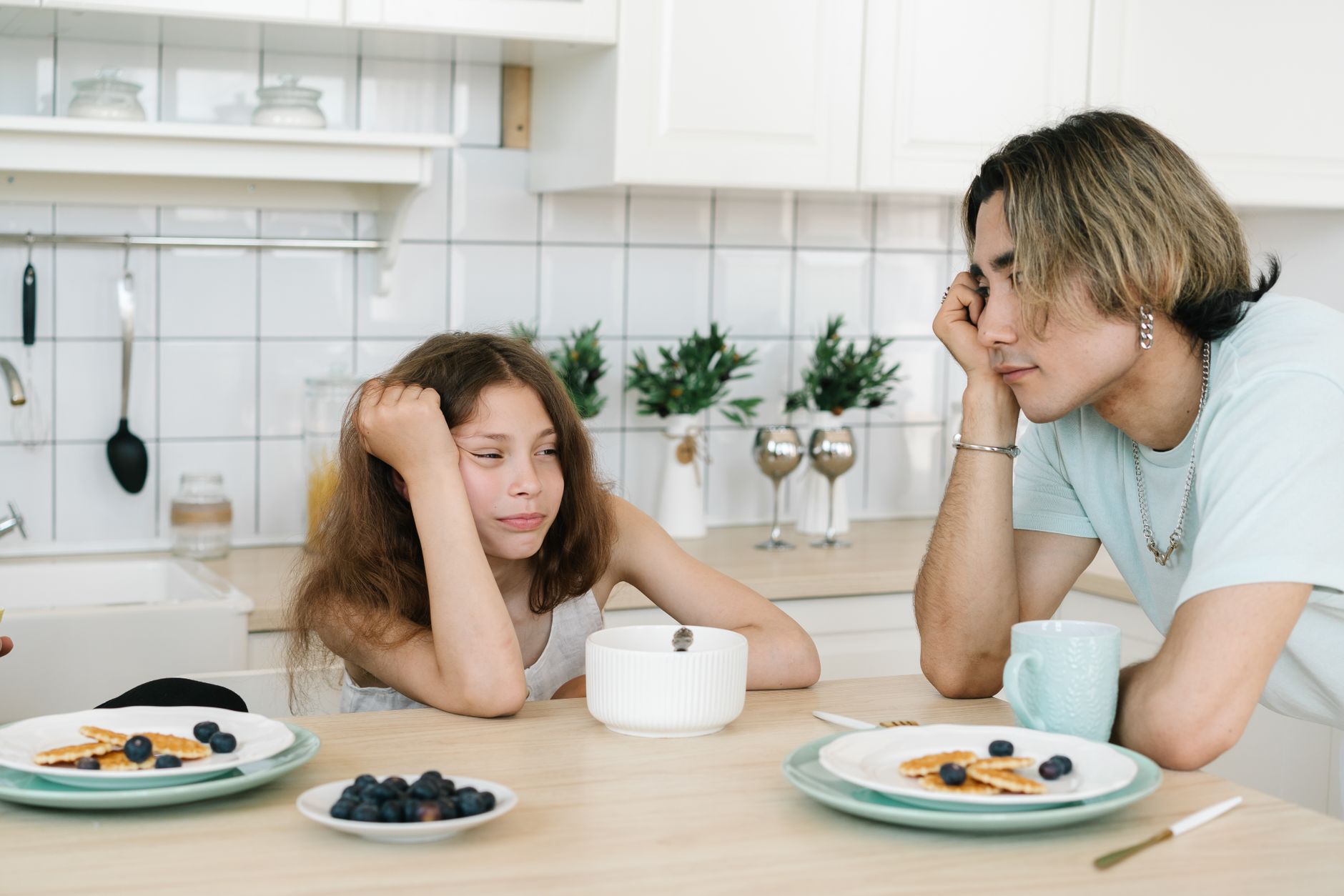 Um pai e uma filha estão sentados à mesa da cozinha tendo uma conversa durante o café da manhã.