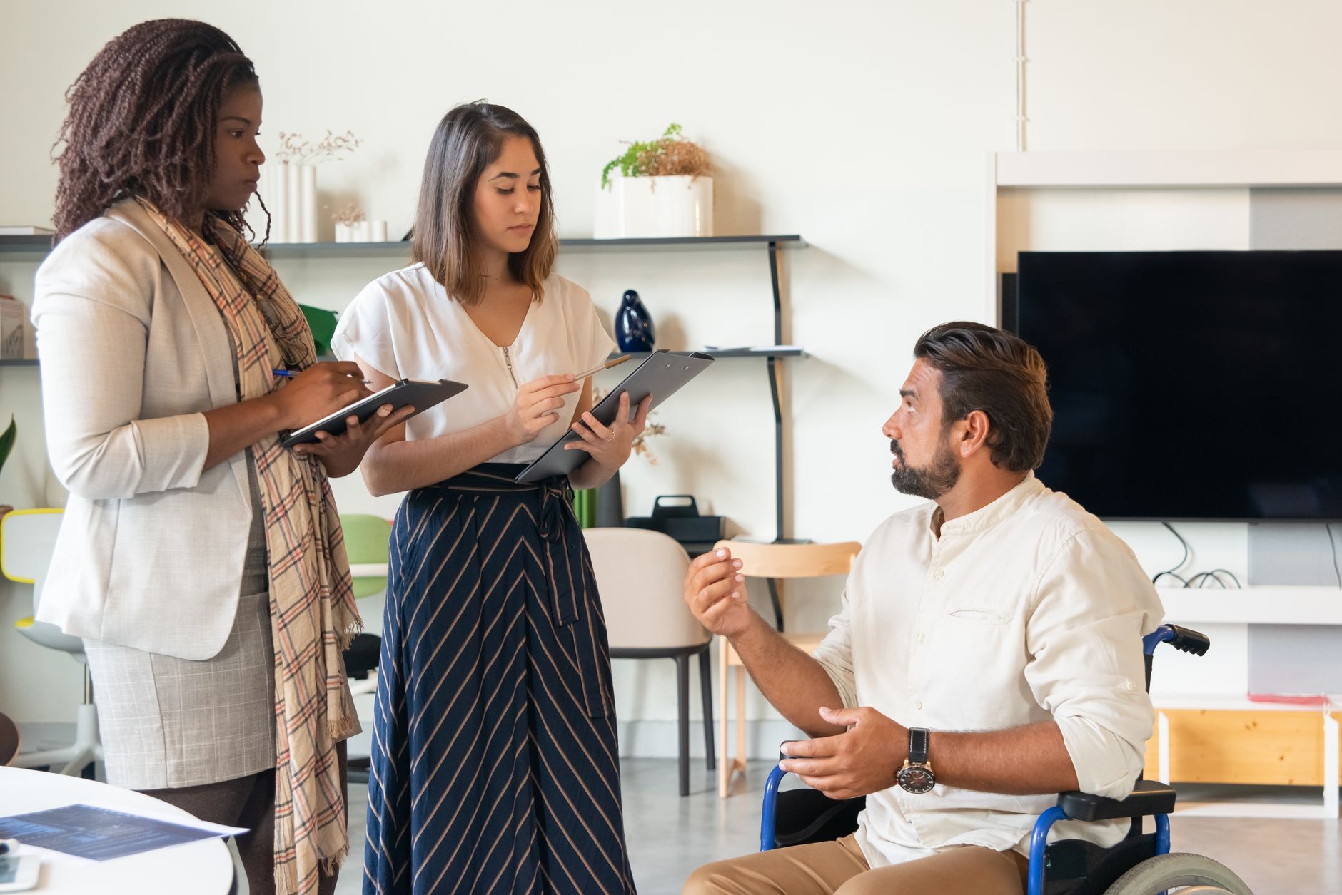 Três colegas de trabalho em um escritório contemporâneo discutindo, promovendo o trabalho em equipe e a inclusão.