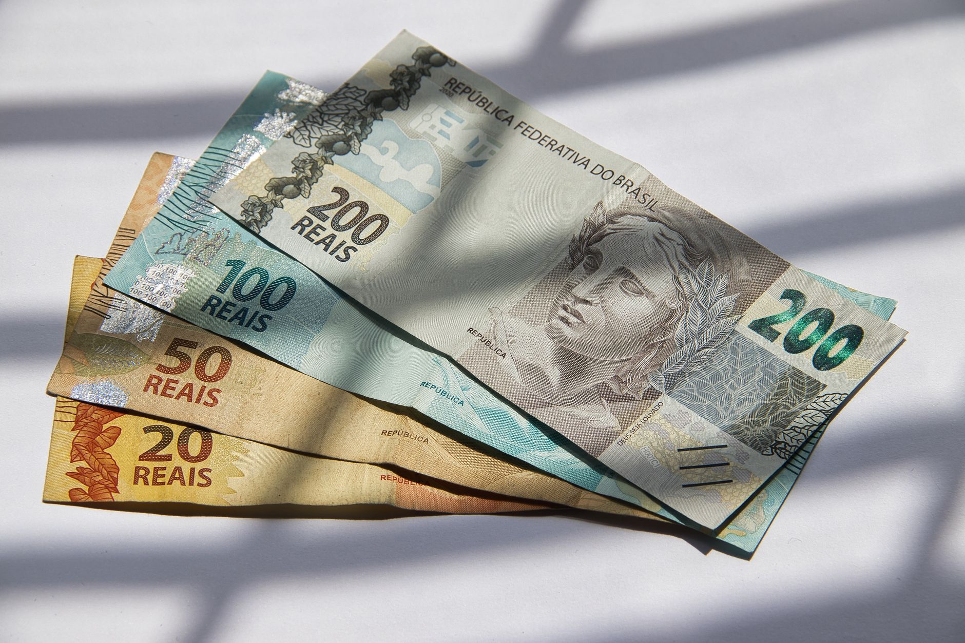 Vários reais brasileiros em luz do sol, destacando a variedade de moedas.