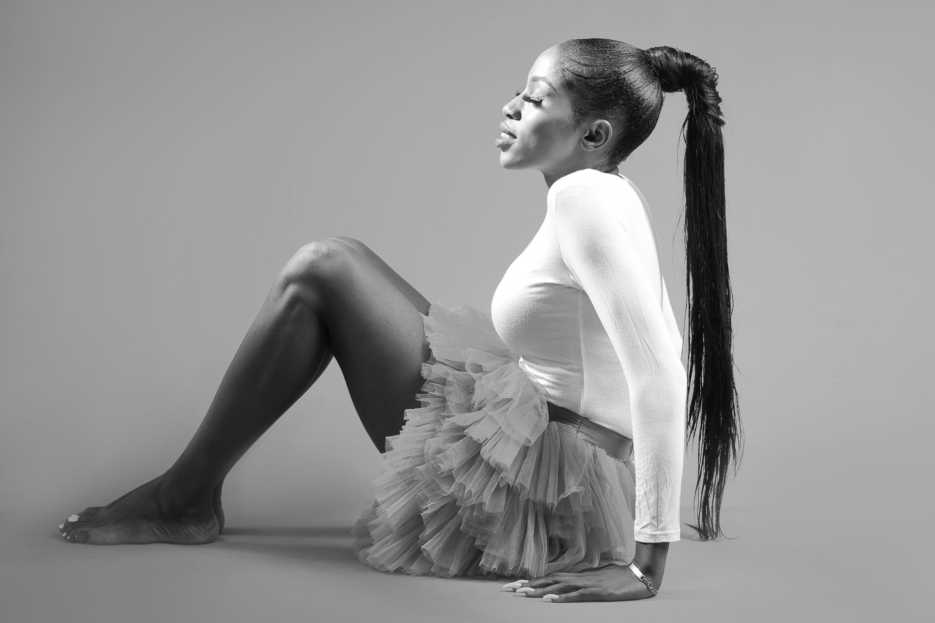 Foto estilosa em preto e branco de uma mulher em um tutu posando graciosamente.