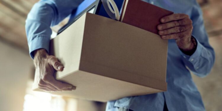 Pessoa tirando próprios pertences de uma empresa após demissão